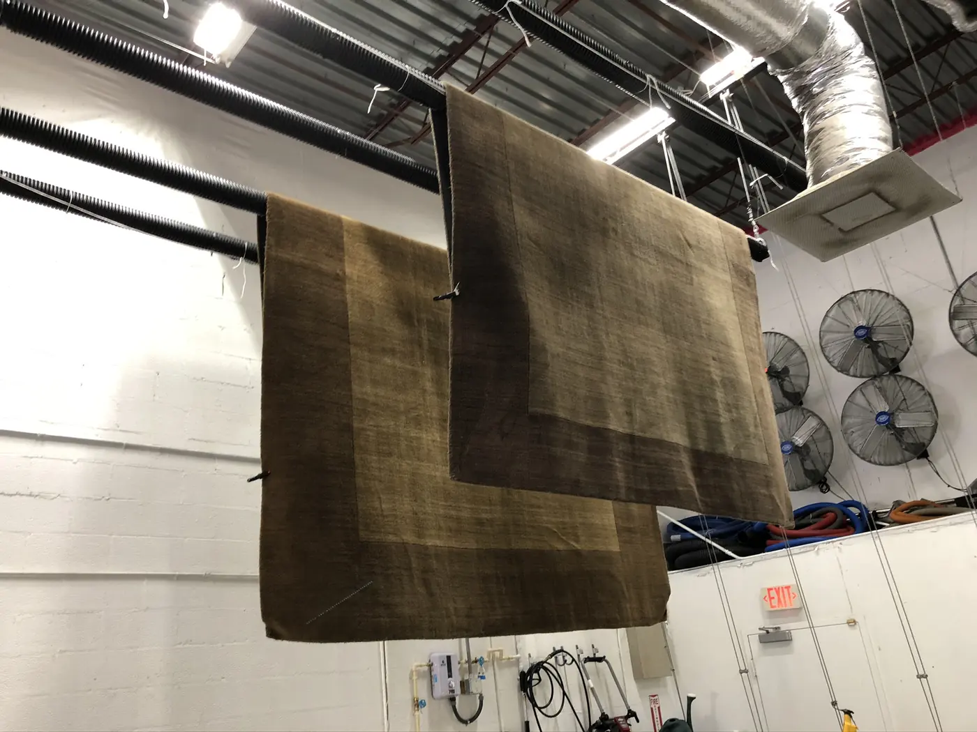 Two rugs hanging from an overhead bar to dry