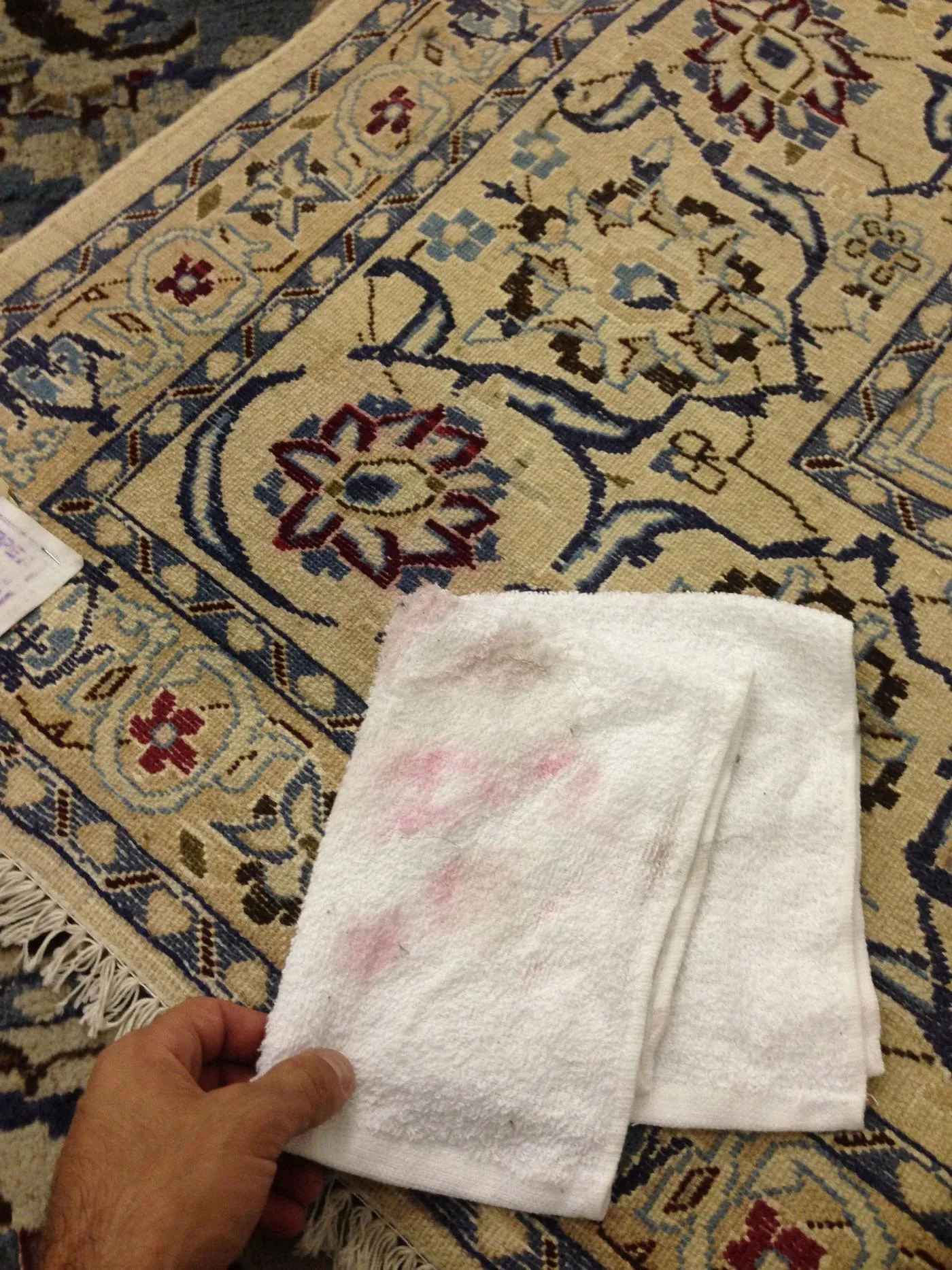 White towel showing red dye transfer from a rug during a dye-stability test